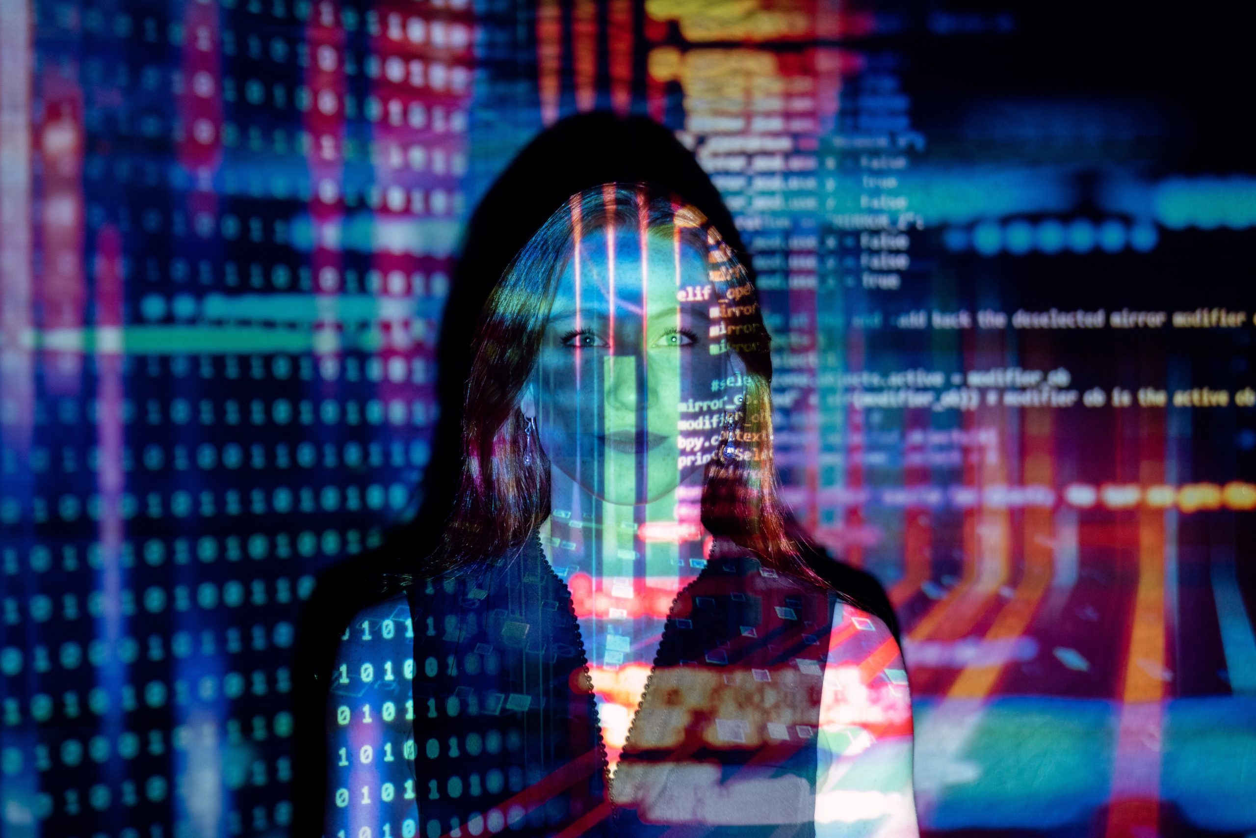 A picture of a woman standing in front of a projector that is shining plenty of alphanumeric strings across her face and the wall behind her. Like database security, any data administrator knows the amount of sheer information involved in managing database servers.