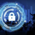 presenter speaking to an audience. The presenter is pointing to a large display of a lock symbolizing cybersecurity in this case as we dive into the lessons learned about vulnerabilities in 2021.