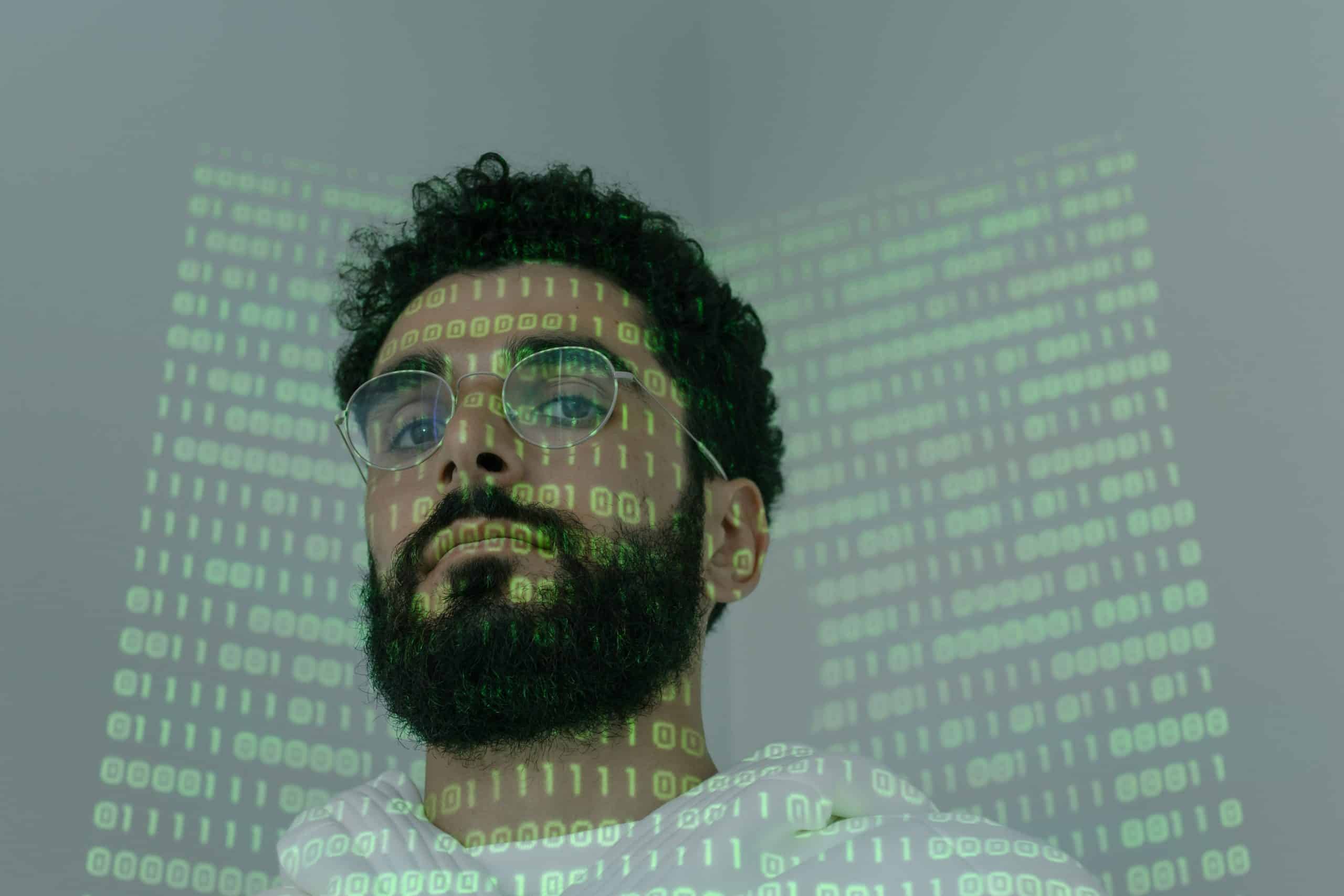 A man stands in a dark room with light green computer projected on his face. Who is this man? What is their plan? This article is about the latest network security tools, known as network detection and response or NDR software using AI and ML for advanced security analytics and inside threat detection and response.