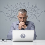 A man thinking while in front of his laptop.