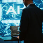 AI system administrator using laptop device in high tech futuristic workspace.