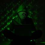 toned picture of hacker silhouette in hoodie using lapto