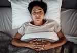 A woman in bed struggling to sleep.